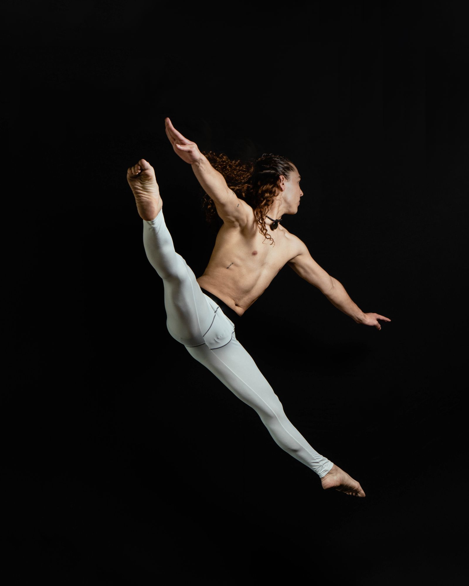 Dancer mid-leap against a black backdrop