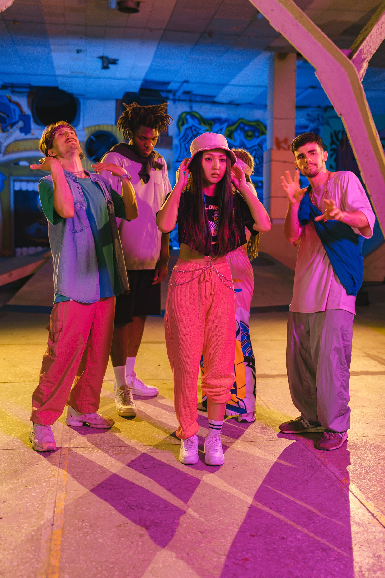 Hip-hop crew posing under neon lights in a graffiti-covered garage